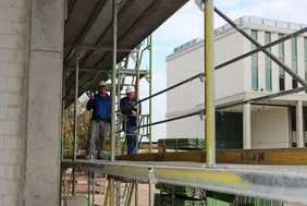 Above all, it was also their celebration: the craftsmen and women made a decisive contribution to the success of the project (Photo: THI). Bild von zwei Männern auf dem gerüst des Digitalbaus beim Richtspruch