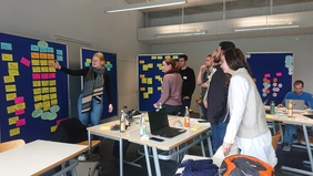 Eine Gruppe Studierender präsentiert ihre Ergebnisse des Workshops an der Pinnwand. 