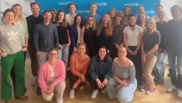 Ein Gruppenbild mit Blauer Unicef-Werbetafel im Hintergrund.