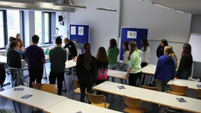 Die Professorin erklärt einer Gruppe Schüler den Versuch. 
