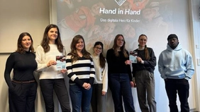 Sieben Personen lächeln in die Kamera, drei von Ihnen zeigen Flyer.