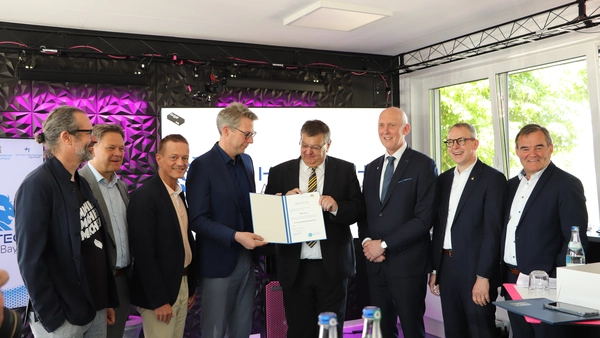 StM Markus Blume überreicht den beteiligten Partnern die Urkunde zum Technologietransferzentrum "Unbemannte Flugsysteme" in Manching.