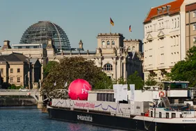 Auf großer Fahrt: Das Ingolstädter Exponat war knapp 3.000 Kilometer durch Deutschland und Österreich unterwegs (© Foto: Ilja C. Hendel/Wissenschaft im Dialog). Bild mit Blick auf das schwimmende Science Center der MS-Wissenschaft auf der Spree, im Hintergrund das Reichstagsgebäude