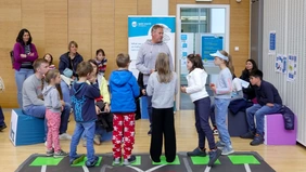 Ein Mann spricht mit einer Gruppe Kinder, die Eltern beobachten das Spiel.