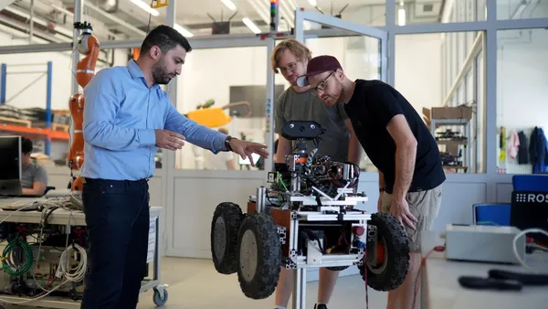 Bild aus dem Futurelab-Labir, wo Herr Kanso zwei Studierenden etwas anhand eines Roboters erklärt 
