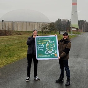Two young people hold up a poster.