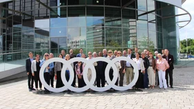 A group photo at the large Audi sign at the Audiforum Ingolstadt.