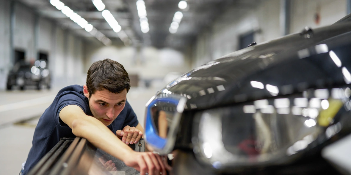 Versuchshalle, Mann untersucht Fahrzeugmotorhaube