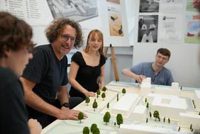 Ein Raum voller Möglichkeiten: Professor Tom Siegel (2. v. l.) diskutiert mit Studierenden Ideen für das Quartier G (Foto: THI/Franziska Märkl). Personen, die um ein Modell des THI Campus sitzen
