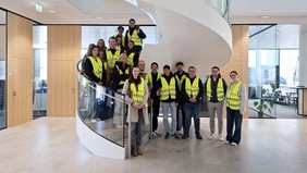 Gruppenfoto auf einer Wendeltreppe, alle Personen tragen gelbe Warnwesten.