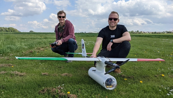 Pelikan auf der Wiese mit zwei Männern beim Außenflugtag