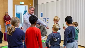 Ein Mann erklärt einer Gruppe Kinder ein Spiel.