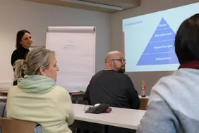 Die Teilnehmerinnen und Teilnehmer der Tagung diskutierten über eine nachhaltige Zukunft (Foto: THI). Bild aus einem Workshop, auf dem zwei Teilnehmende und die Leiterin des Workshops zu sehen sind