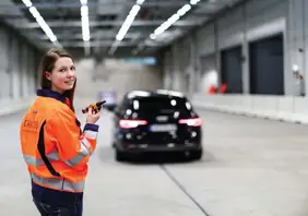 Frau in Warnweste mit Funkerät im Carissma, im Hintergrund schwarzer PKW